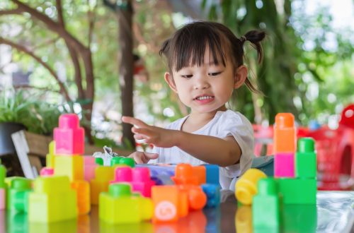 Portrait image of 3-4 toddler kid. Happy Asian child girl playing the plastic block toys. Learning and education concept. Smiling little baby.